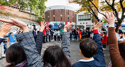 KCU 가을축제 두번째 이미지, 상담심리학과와 청소년상담학과 등 대학교 학과별 파란색 천막 부스들이 줄지어 설치되어 있고, 사람들이 모여 체험 및 상담 활동을 하고 있는 야외 행사 현장