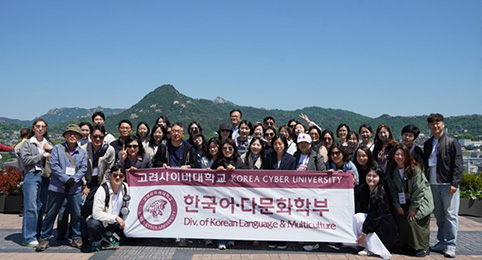 학부별 모꼬지(MT) 첫번째 이미지, 맑은 하늘과 푸른 산을 배경으로 고려사이버대학교 한국어·다문화학부 현수막을 들고 단체 사진을 촬영하고 있는 학생들의 모습