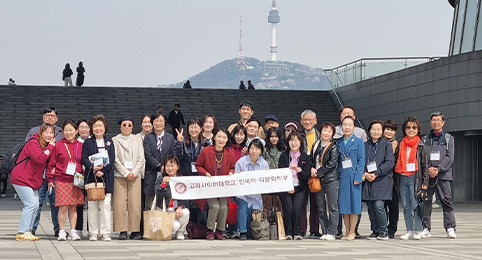 학부별 모꼬지(MT) 두번째 이미지, 멀리 남산 N서울타워가 보이는 국립 중앙 박물관 야외 광장에서 고려사이버대학교 한국어·다문화학부 현수막을 들고 단체 사진을 촬영하고 있는 사람들의 모습